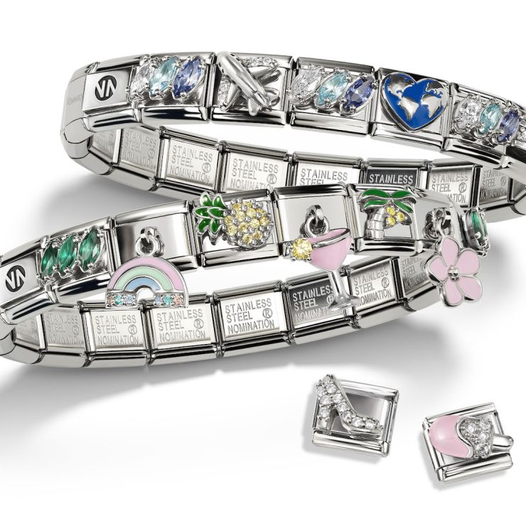 Zwei Composable Armbänder aus Edelstahl mit bunten Charms wie Regenbogen, Ananas, Blume, Cocktailglas, Herz, Flugzeug und Weltkugel. Ergänzt durch einzelne Schmuckelemente in Form eines Schuhs und einer Handtasche.