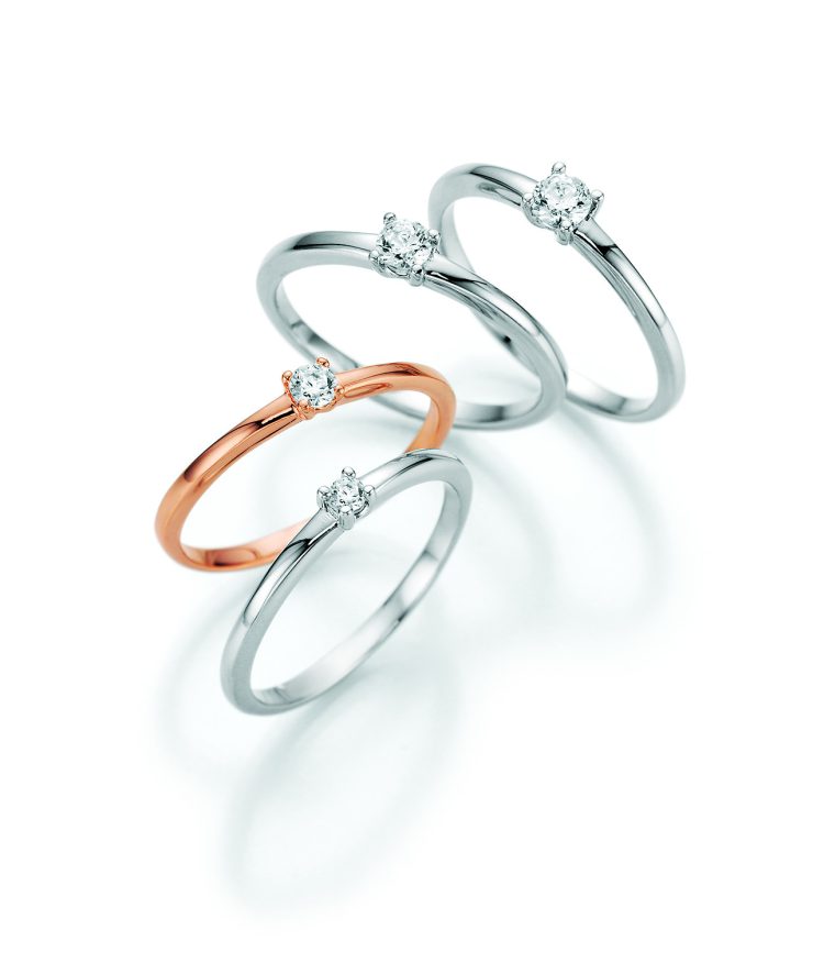 Vier elegante Solitärringe in Weißgold und Roségold mit jeweils einem funkelnden Diamanten in Krappenfassung. Die zeitlosen Ringe präsentieren klassische Schmuckdesigns für Verlobung, besondere Anlässe oder den täglichen Stil.
