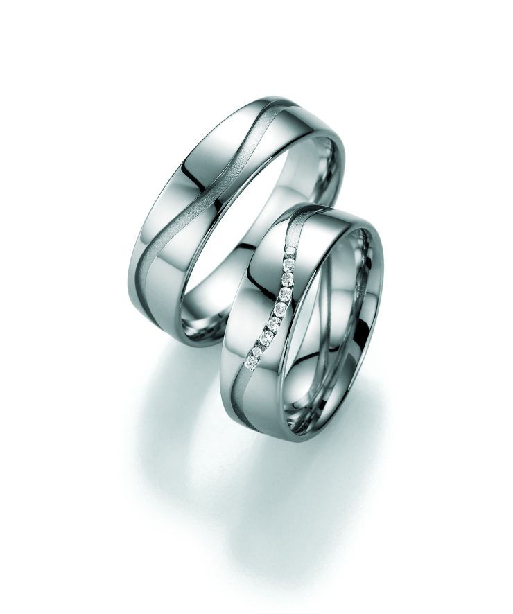 Elegantes Partnerring-Set in Silberoptik mit geschwungenem, mattiertem Designelement auf hochglanzpolierter Oberfläche. Einer der Ringe ist mit einer Reihe funkelnder klarer Zirkonia-Steine besetzt und verleiht dem Set eine edle, moderne Ausstrahlung. Ideal als Trau-, Verlobungs- oder Freundschaftsringe.
