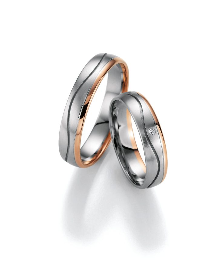 Modernes Partnerring-Set in Silber- und Roségoldoptik mit sanft geschwungenem Design. Die matte silberfarbene Oberfläche wird durch roségoldfarbene Akzente an den Seiten elegant ergänzt. Einer der Ringe ist mit einem funkelnden klaren Zirkonia besetzt und verleiht dem Set eine edle, zeitlose Ausstrahlung. Ideal als Trau-, Verlobungs- oder Freundschaftsringe.