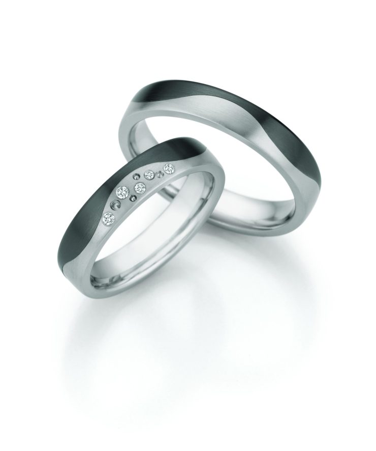 Elegantes Trauring-Set in moderner Titanoptik mit harmonisch geschwungenem Design in mattierten und polierten Oberflächen. Der Damenring wird durch mehrere funkelnde Diamanten stilvoll veredelt, während der Herrenring die klare Linienführung aufgreift. Eine ausdrucksstarke Kombination aus zeitgemäßer Ästhetik, Beständigkeit und symbolischer Verbundenheit.