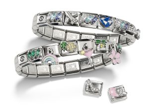 Zwei Nomination Composable Edelstahlarmbänder mit bunten Charm-Elementen wie Weltkugel, Regenbogen, Ananas, Cocktailglas, Blume und funkelnden Schmuckdetails sowie zwei einzelne Charm-Module