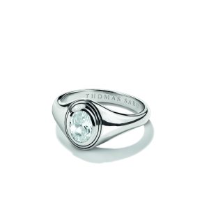 Ausdrucksstarker Ring aus poliertem Silber mit einem ovalen, facettierten weißen Schmuckstein in moderner Zargenfassung. Die breite, sanft zulaufende Ringschiene im Siegelring-Stil verleiht dem Design eine elegante und zugleich markante Ausstrahlung. Zeitloses Schmuckstück mit klassischer Formensprache, präsentiert auf hellem Hintergrund