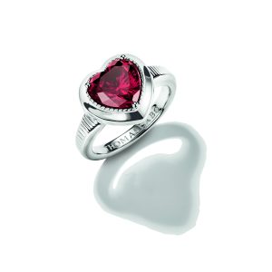 Romantischer Ring aus poliertem Silber mit einem großen herzförmigen Schmuckstein in intensivem Rubinrot. Der facettierte Stein ist in einer herzförmigen Fassung mit feinen Zierdetails eingefasst und wird von einer eleganten Ringschiene mit dezenten Rillenakzenten getragen. Die Kombination aus glänzendem Silber und dem leuchtend roten Herz verleiht dem Schmuckstück eine ausdrucksstarke und liebevolle Ausstrahlung. Präsentiert auf hellem Hintergrund mit dekorativem Schatten.