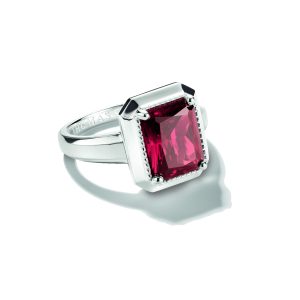 Markanter Ring aus poliertem Silber mit einem großen rechteckigen Schmuckstein in intensivem Rubinrot. Der facettierte Stein ist in einer auffälligen geometrischen Fassung mit feinen Zierdetails eingefasst und wird von einer breiten, leicht geteilten Ringschiene getragen. Die Kombination aus glänzendem Silber und leuchtendem Rot verleiht dem Schmuckstück eine elegante und ausdrucksstarke Wirkung. Präsentiert auf hellem Hintergrund.