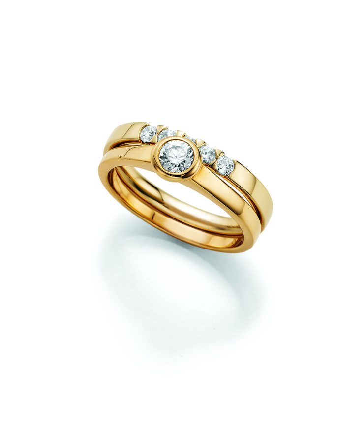 Eleganter Ring aus Gelbgold mit zentralem Brillanten in Zargenfassung, flankiert von weiteren Diamanten auf der oberen Ringschiene. Das zweiteilige Design verleiht dem Schmuckstück eine moderne und luxuriöse Ausstrahlung.