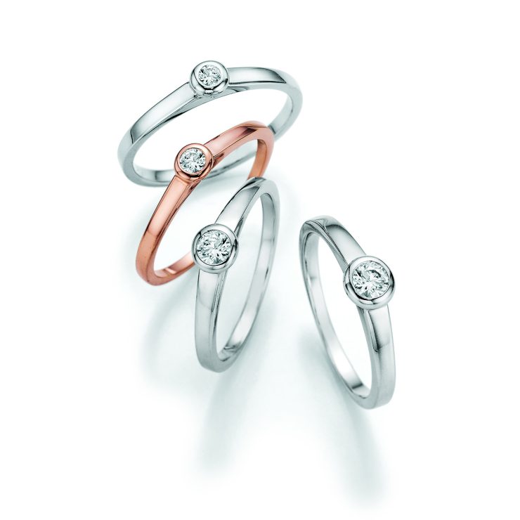 Filigrane Solitärringe in Weißgold und Roségold mit zentral gefasstem Brillanten in eleganter Zargenfassung. Zeitlose Schmuckstücke mit puristischem Design und funkelnder Ausstrahlung für jeden Anlass.